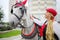 Coachman happy blonde stands with horse in red