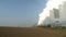 Coal-fired power plant at the edge of the field emits smoke