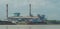 Coal power plant on riverbank with barge full of coal in the dock. Indonesia