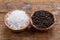 Coarse crystal salt and whole black peppercorns in small wooden bowls