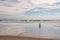 The coast of the Atlantic Ocean at low tide and a pair of elderly people strolling along the sand.