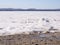 Coast of frozen lake under snow and mountains on a skyline. Blue sky, sunny cloudless day, early spring