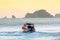 Coast Guard motorboat sails from shore. Sunset sky and mountains in the background. Man drives a lifeguard ship