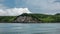 The coast of Kamchatka. Against the background of a blue sky with clouds - green hills