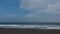 The coast of the Pacific Ocean. Surf waves foam on the black volcanic sand