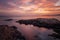 Coast sea. Sunset. Sunrise. Wild rock beach. The natural rock formation. Red sun over summer sea. Cloud on a blue sky over summer