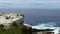 Coast of the sea with waves crashing on the rocks. Mount with grass and limestone