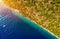 Coastal area with blue clear water and forest on land, aerial view taken by drone. Half land half sea on a diagonal line. A