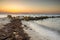 Coastal Dreamscape: Rocky Shoreline and Seaweed-Strewn Beach under the Sunset Sky