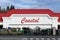 Coastal Farm and Ranch store with red sign and roof and white wall with supplies outside