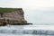 Coastal landscape in Northern Angola with rocky cliff, small waves and white light, N`zeto, Africa