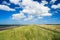 Coastal landscape under a sunny blue sky with fluffy white clouds