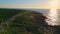 Coastal road summer sunset over rocky shore. Drone view cars riding on seashore.