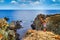 Coastal rocky landscape - the girl hands raised up to sky celebrating freedom