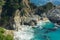 Coastal waterfall cascading onto Pacific white sand beach surrounded by rocky cliffs