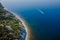 Coastline with blue sea, cliff with pine trees and motor boat. Summer da. Aerial view