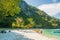 Coastline of tropical island with huge mountains and tourists, kayakers on the beach