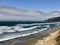 Coastline, waves crashing on the sand, with blue sky