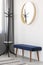 Coat hanger, blue settee and round mirror in wooden frame in spacious hall