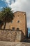 Cobblestone alley with stone wall, old building and palm tree at Caceres