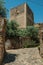 Cobblestone pathway going toward a stone wall and tower