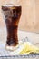 Coca cola in glass with potato chips