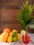 Cocktail, oranges, lemons, limes, mango, vase with leaves on a brown background