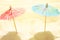 Cocktail paper umbrellas on beach sand in golden sunlight. Creative artistic stylized image. Summer seaside vacation relaxation