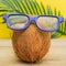 A cocnut wearing 3D glasses on blue background. Summer and trave concept