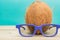 A cocnut wearing 3D glasses on blue background. Summer and travel concept