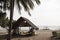 Coco palm tree and bamboo gazebo on the beach against white sky and sea. Asian tropical island neutral photo background