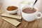Cocoa in bowl, pitcher with milk, wafers with porous chocolate, cup of cocoa with milk, spoon on wooden table