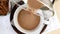 Cocoa drink is poured into cup, spoon on saucer. Natural delicious hot chocolate. Alternative healthy caffeine for breakfast.