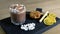 Cocoa with marshmallow in rock glass on a wood black tray with cake and lemon. Close-up side view.