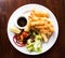 Coconut battered prawn shrimps served with hot chips and salad on white plate