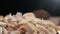 Coconut chips are falling down to wooden bowl close-up