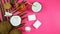 Coconut cosmetics with soaps, moisturizers, beauty products on pink background.