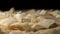 Coconut flakes lie on the table. Black background at the back. Coconut flakes rotate on a turntable, extreme close up