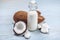 Coconut milk in a bottle with white flesh on a blue wooden background. Organic product used in cosmetology