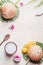 Coconut oil in wooden bowl with spoon and moisturizing cream on white desk background with tropical leaves and flowers , top view