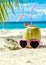 Coconut, pink sunglasses and seashell on sand close-up