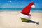 Coconut in Santa Christmas hat sand tropical beach