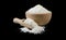 Coconut shreds in wooden bowl and scoop isolated on black background. Spices and food ingredients