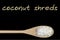 Coconut shreds on wooden spoon isolated on black background
