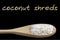 Coconut shreds on wooden spoon isolated on black background