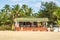 coconut trees on ocean coast near tropical shack or open cafe on beach with sunbeds