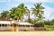 coconut trees on ocean coast near tropical shack or open cafe on beach with sunbeds