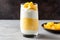 coconut yogurt mixed with diced mango in a tall glass