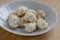 Coconuts made of egg whites, sugar and shredded coconut on white plate on wooden table, group of Christmas sweets