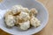 Coconuts made of egg whites, sugar and shredded coconut on white plate on wooden table, group of Christmas sweets